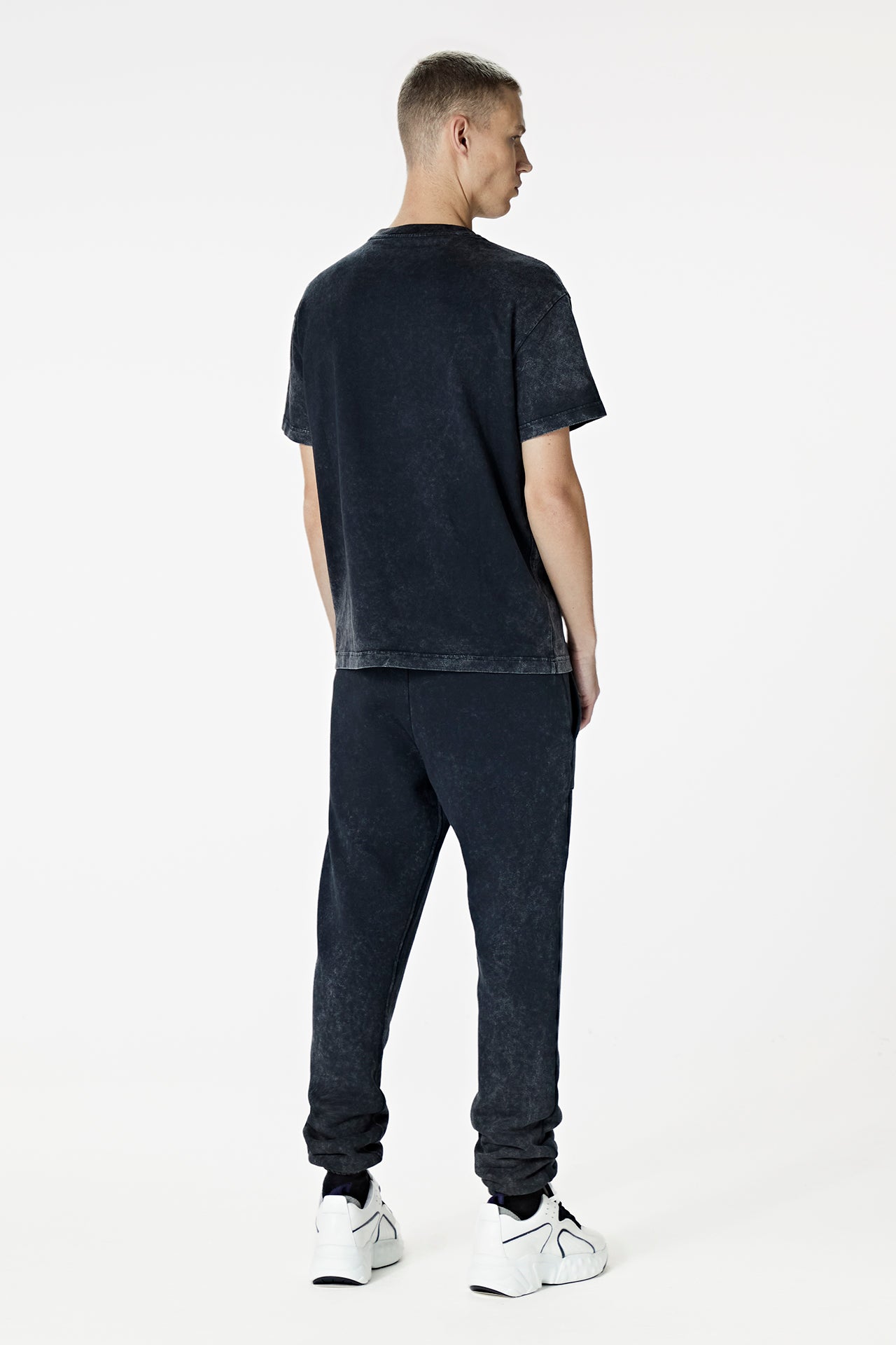 Male Model wearing the washed black tee-shirt- BODA SKINS. Back Facing.
